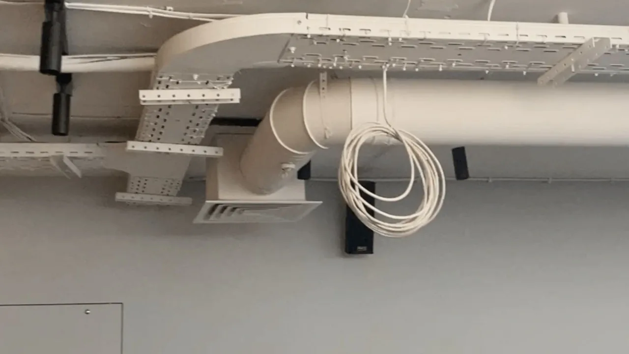 Оцинковані вентиляційні канали та повітропроводи в офісі поруч із внутрішнім блоком кондиціонера.