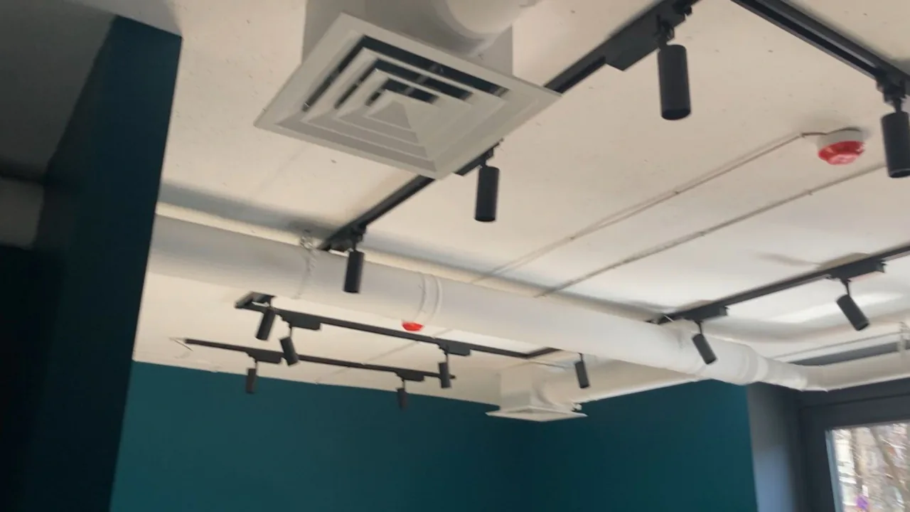 Промислова вентиляція: мережа білих круглих повітропроводів та внутрішній блок кліматичної системи Haier.