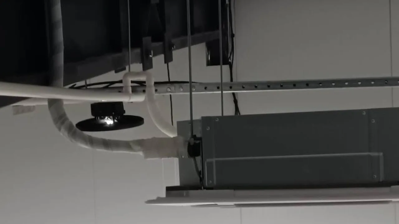 Ventall specialist on scaffolding installing a large ducted air-conditioning unit suspended from the concrete ceiling.